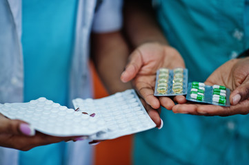 Two african american pharmacist working in drugstore at hospital pharmacy. African healthcare. Close up pills on hands.