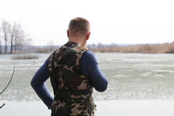 Naklejka premium The man stares into the distance while standing on the shore of the la