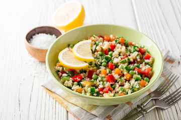 Fresh salad with bulgur and vegetables on white wooden table