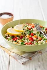 Fresh salad with bulgur and vegetables on white wooden table