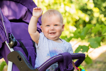 A small child is sitting in a stroller. walk with the child in the open air