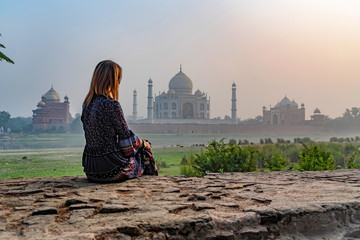 Obraz premium Beautiful girl looks at Taj Mahal. Travel concept