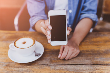 hand woman using smartphone in coffee shop and soft light with vintage filter.