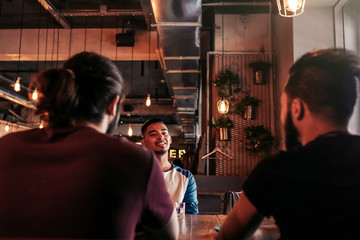 Group of mixed race young men talking and laughing in lounge bar. Multiracial friends having fun in cafe. Guys hang out