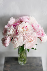 Cute and lovely peony. many layered petals. Bunch pale pink peonies flowers light gray background. Wallpaper, Vertical photo
