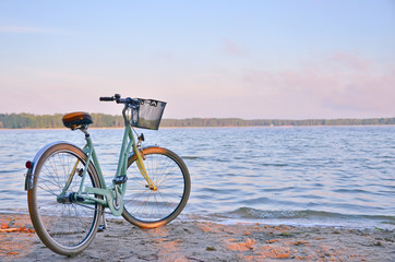Vintage bicycle with a basket near the lake during beautiful summer sunset. Copy space. © kyrychukvitaliy