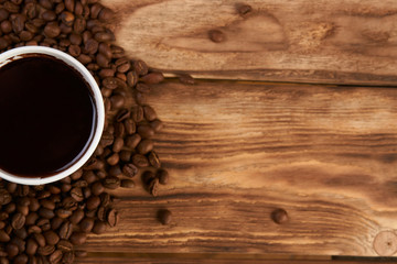 Take away coffee paper cup with hot chocolate drink and roasted coffee beans on wooden table background with copy space, top view, close-up