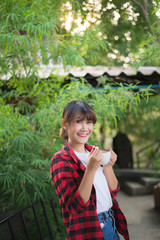 asian beautiful woman drinking hot coffee or tea in the green garden