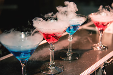 Blue and red cocktails with the effect of smoke and steam from the reaction of dry ice vapor. Bartender barman show.