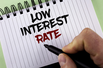 Text sign showing Low Interest Rate. Conceptual photo Manage money wisely pay lesser rates save higher written by Man on Notepad holding Marker on the plain background.