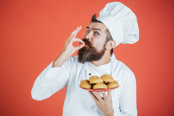Baking, cooking, gesture and food concept - happy satisfied bearded chef, cook or baker gesturing excellent. Bearded chef holds plate of oatmeal cookies showing sign delicious. Meal is just perfect!