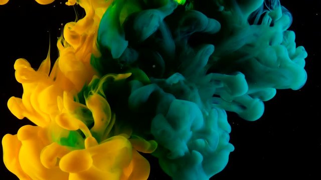 Yellow green ink in water shooting with high speed camera. Blue paint dropped, reacting, creating abstract cloud formations and metamorphosis on black. Art backgrounds. Slow motion