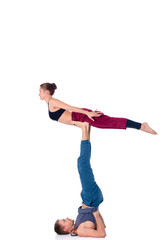 Young athletic couple practicing acroyoga. Balancing in pair.