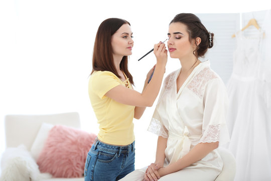 Professional makeup artist working with young bride in salon