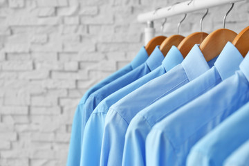 Rack with clean clothes on hangers after dry-cleaning indoors