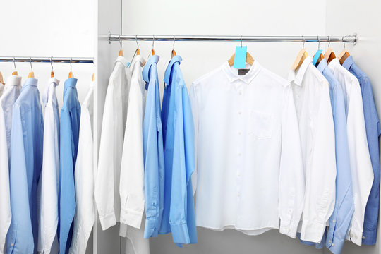 Racks with clean clothes after dry-cleaning on hangers in wardrobe