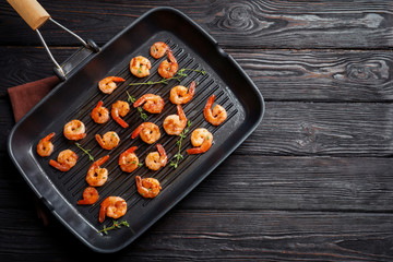 Grill pan with delicious fried shrimps on wooden background, top view