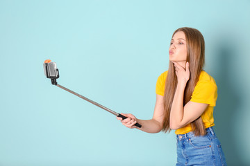 Young beautiful woman taking selfie against color background