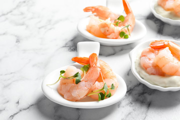 Bowls with boiled shrimps and sauce on light background