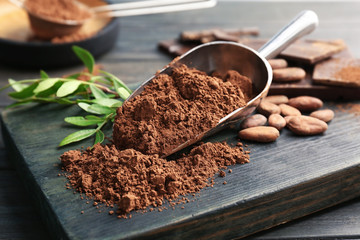 Scoop with cocoa powder on wooden board