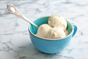 Cup with tasty vanilla ice cream on light background