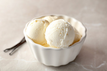 Bowl with tasty vanilla ice cream on light background