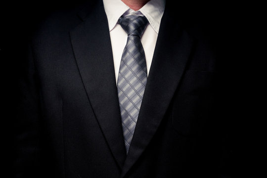 Close Up Of Man In Black Suit, Shirt And Tie On Black Background