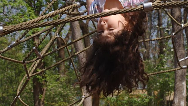Slow motion of 10 years old girl hanging upside down on jungle gym, 4k
