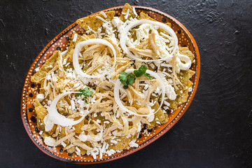 chilaquiles mexican spicy food, avocado, nachos, chicken and cheese mexico on black background