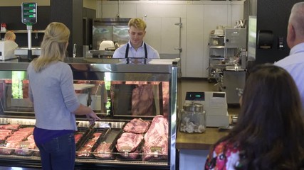 Butcher talking with a mature woman in a butcher shop