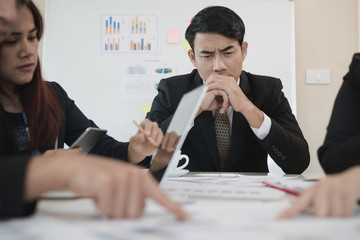 Group Asian Young Businessmen and woman discussing on stockmarket charts at office desk, they are business analyzing. used laptop in the work. brainstorming, teamwork, meeting concept.
