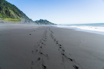 Footsteps in the black sand of the Lost Coast backpacking trail in California