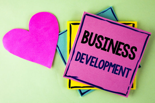 Writing note showing  Business Development. Business photo showcasing Develop and Implement Organization Growth Opportunities written on Pink Sticky Note Paper on plain background Heart next to it.