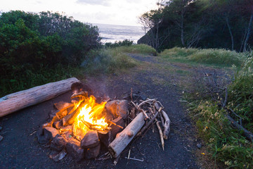 Campfire on grassy overlook on a cliff at sunset on the Lost Coast backpacking trail in California