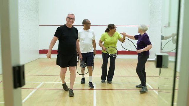 Four people leaving a squash court