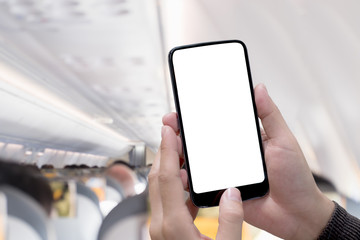 Airplane passenger using smart phone on plane with blank screen and blurred background for graphics display montage.