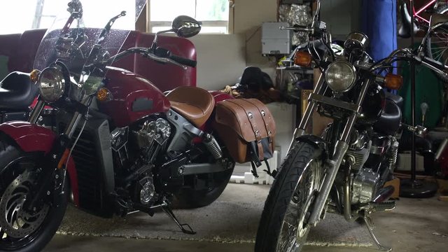 Motorbikes parked in garage, side by side, panning left. 