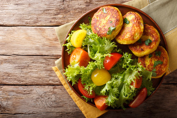 Freshly prepared potato pancakes are served with fresh salad close-up. Horizontal top view