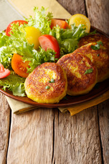 Ecuadorian traditional food: llapingachos potato pancakes and fresh salad close-up on a plate. vertical