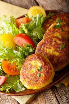 Ecuadorian potato pancakes llapingachos and fresh salad close-up on a plate. vertical