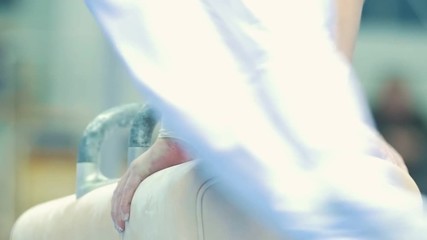 Male gymnasts does exercises at the pommel horse