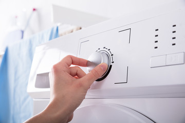 Person Turning Button Of Washing Machine