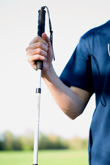 isolated hand of a blind man hold a cane or blind stick, the torso of the blind man is blurred