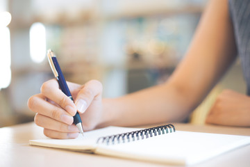 Business woman hand is writing on a note pad with a pen in office.