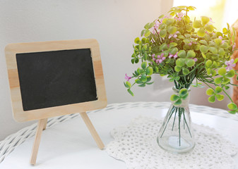Blank Chalkboard with artificial flower on the table.