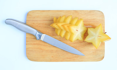Sliced ripe Star apple on wood board background against white background.
