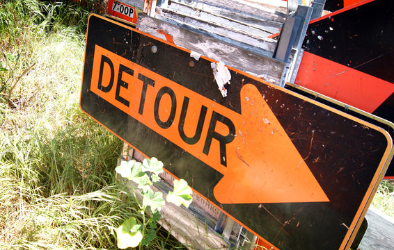 aged and worn detour sign with arrow