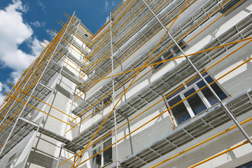 scaffolding near a new house, building exterior, construction and repair industry, white wall and window, yellow pipe