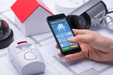 Architect's Hand Using Home Control System On Mobile Phone