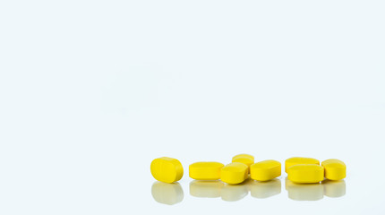 Yellow tablets pills isolated on white background with copy space for text. Ibuprofen tablets pills. Painkiller medicine for headache, high fever and anti inflame. Pharmaceutical industry concept.